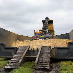 De rupsdumper lossen in een bak op de kopakker.